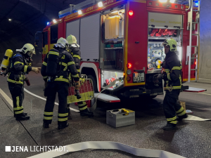 Feuerwehrleute holen Equipment aus einem Feuerwehrfahrzeug.