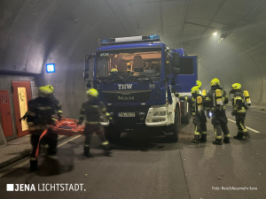 Neben und vor einem THW-Fahrzeug befinden sich rund 6 THW-Mitglieder in Schutzausrüstung und mit einer Trage.