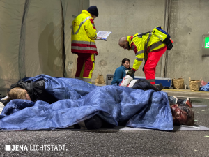 Zwei Statisten liegen Blut überströmt auf dem Boden und sind zugedeckt.