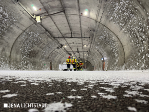 Feuerwehrleute laufen über den mit Löschschaum bedeckten Boden und Löschen das restliche Feuer des Auto.