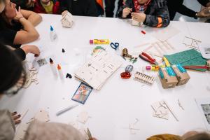 Man sieht Kinderhände auf einem Tisch mit vielen Bastelutensilien.