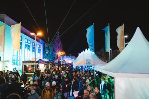 Viele Menschen laufen durch das dunkle und leicht beleuchtete Jena.
