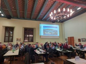 Stadtratsmitglieder im Historischen Rathaus sitzen an Tischen und verfolgen die Debatten