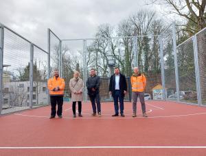 Fünf Personen stehen auf einem Bolzplatz.