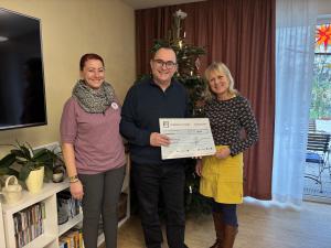 Werkleiter Uwe Feige steht vor einem Weihnachtsbaumund hält einen übergroßen Scheck in der Hand- Christiane Klimsch sthet rechts und Monika Hirche links von ihm