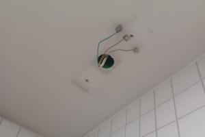 Eine Sicherheistleucht wurde abgerissen und fehlt jetzt an der Decke. Kabel ragen aus einem Lock in der Decke.