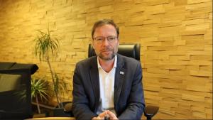 Oberbürgermeister Thomas Nitzsche sitzt an einem Tisch und blickt in die Kamera.