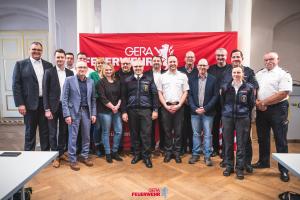 Eine Gruppe von Menschen steht nebeneinander und lacht in die Kamera