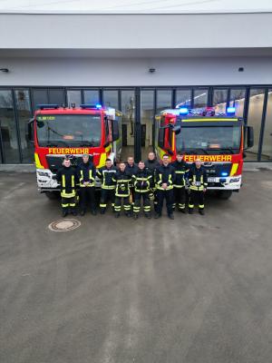 Feuerwehrleute stehen vor zwei Einsatzfahrzeugen an der neuen Rettungswache.