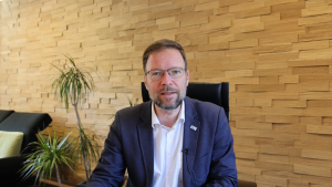 Oberbürgermeister Thomas Nitzsche sitzt an einem Tisch in seinem Büro und schaut in die Kamera.