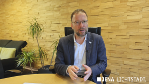 Oberbürgermeister Thomas Nitzsche sitzt in seinem Dienstzimmer am Beratungstisch und spricht in die Kamera.