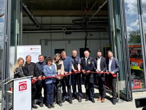 Eine Gruppe aus Männern und Frauen zerschneidet rotes Band.