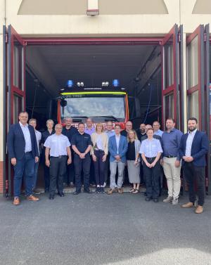 Viele Menschen stehen vor einer Feuerwache und schauen in die Kamera.