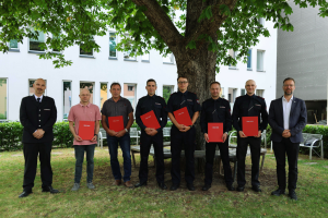 OB und Feuerwehrmänner schauen in die Kamera.