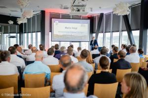 Ein Mann spricht vor Publikum in ein Mikrofon