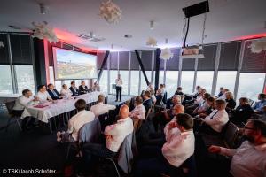 Ein Mann spricht in ein Mikrofon vor einem Publikum.