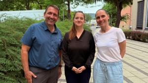 Drei Personen lächeln in die Kamera