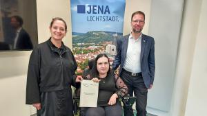 Drei Personen mit einer Broschüre