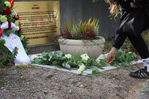 Frau legt Blume an Gedenkstelle ab