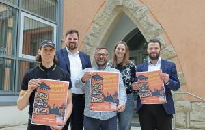 Fünf Personen halten drei Plakate in die Kamera.