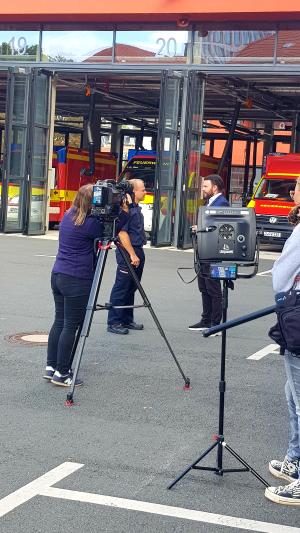 Bürgermeister Koppe und Feuerwehrmann Dietz im Gespräch, gefilmt von einem Kamerateam.