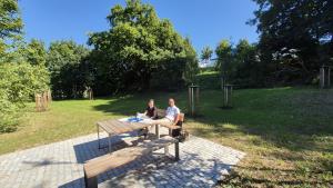 Naturnahe Lichtung mit Rastplatz: Eine Frau und ein Mann sitzen in der Sonne auf einer Bank.
