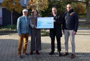 v.l.: Friedrich Wilhelm Gebhardt, ehemaliger Ortsteilbürgermeister von Jena-Winzerla, Ostbeauftragte Elisabeth Kaiser, Oberbürgermeister Thomas Nitzsche und Lars Liebe, Fachdienstleiter Stadtentwicklung stehen nebeneinander und halten einen großen Scheck.
