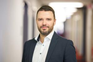 Mann steht in einem Innenraum und lächelt