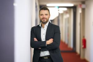 Man steht mit verschränkten Armen in einem Flur angelehnt