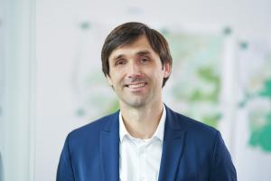 Mann in blauem Anzug steht in einem Raum und lächelt