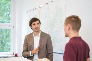 Mann in braunem Anzug in einer Gesprächssituation