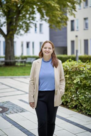 Frau steht im Außenbereich und lächelt in die Kamera