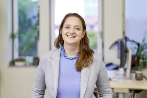 Frau sitzt an einem Tisch und lächelt in die Kamera