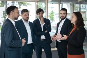 Vier Männer und eine Frau stehen in einer Gesprächssituation beieinander