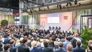 Viele Menschen sitzen im Publikum und hören Podiumsdiskussion zu.