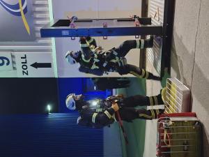 Zwei Feuerwehrmänner üben, eine Tür zu öffnen.