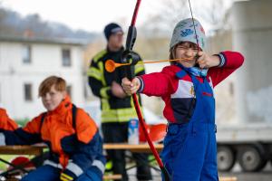 Kind schießt mit Pfeil und Bogen.