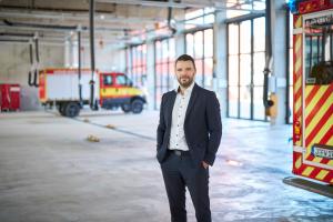 Mann in blauem Anzug steht in einer Halle mit Feuerwehrfahrzeugen