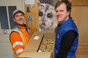 Zwei Männer halten eine Umzugskiste, die gefüllt ist mit Korken.