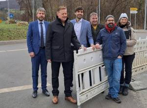 Sechs Personen stehen an einer geöffneten Absperrung.