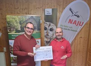 Eine Person überreicht eine anderen eine Spendenquittung.