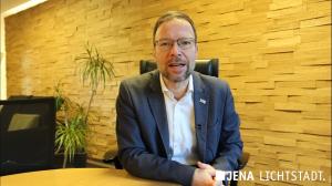 Ein Mann sitzt an einem Tisch und blickt in die Kamera.