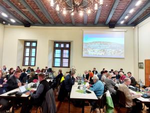 Stadtratsmitglieder sitzen an Tischen im Historischen Rathaus während der Stadtratssitzung