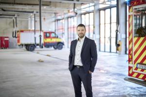 Bürgermeister Benjamin Koppe schaut in der Fahrzeughalle der Feuerwehr die Kamera.