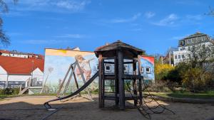 Blick auf einen kleinen Spielplatz mit Rutsche, Schaukel und Kletterturm