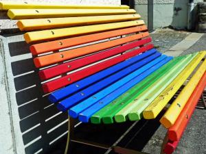 Eine Parkbank, die regenbogenfarben gestrichen ist.