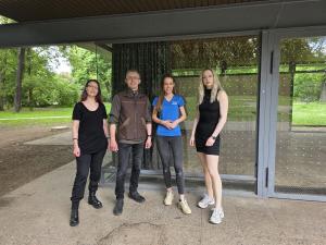 Ein Mann und drei Frauen stehen vor einer Glasfront, die mit Punktfolie gegen Vogelschlag beklebt ist.