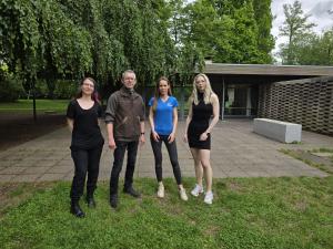 Ein Mann und drei Frauen stehen mit etwas Abstand vor dem Glashaus im Paradies.