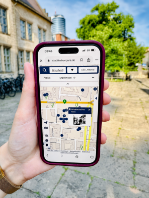 Hand hält Smartphone, auf dem eine Stadtkarte zu sehen ist. 