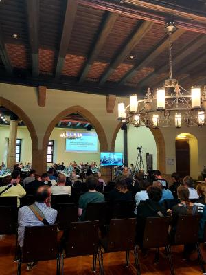 im großen Saal des historischne Rathauses sitzen Menschen auf Stühlen und an Tischen während der Stadtratssitzung